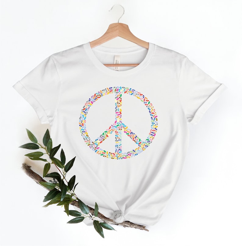 May include: White t-shirt with a peace sign made of colorful leaves.