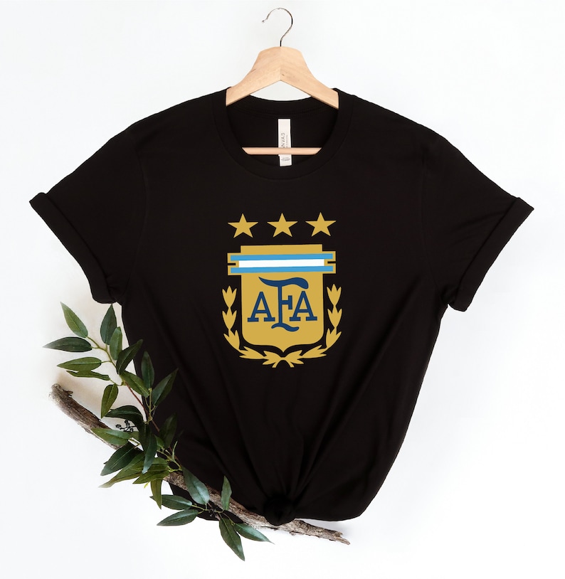 May include: Black t-shirt with a gold and blue crest featuring the letters "AFA" and three stars.