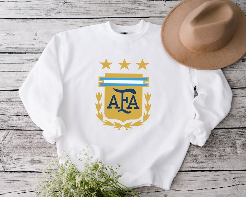 May include: White sweatshirt with a gold and blue crest featuring the letters "AFA" and three stars.