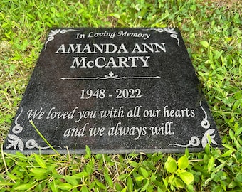Puede incluir: Una lápida de granito negro con texto blanco grabado. La inscripción dice "In Loving Memory AMANDA ANN McCARTY 1948-2022 We loved you with all our hearts and we always will." Acentos florales decorativos.