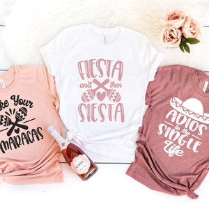 Puede incluir: Tres camisetas con diferentes diseños para una despedida de soltera. La primera camiseta es de color melocotón con el texto "Shake Your Maracas" y un gráfico de dos maracas. La segunda camiseta es blanca con el texto "Fiesta and then Siesta" y un gráfico de dos maracas. La tercera camiseta es granate con el texto "Adios to the Single Life" y un gráfico de un sombrero.