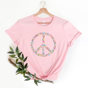 May include: A pink t-shirt with a peace sign made of colorful confetti.
