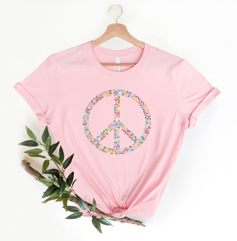May include: A pink t-shirt with a peace sign made of colorful confetti.
