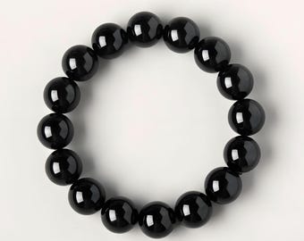 May include: A black beaded bracelet. The bracelet is made of smooth, round, polished black beads. The beads are strung together to form a circular shape. The bracelet is displayed on a white background.