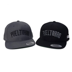 May include: Two baseball caps with the word "PUELTORRO" embroidered on the front. One cap is gray and the other is black.