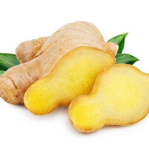 May include: A close-up of a ginger root with two slices, showing the light yellow flesh. The ginger root is surrounded by green leaves.