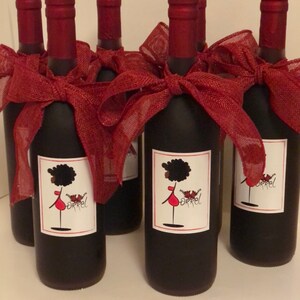 May include: Six bottles of wine with red ribbon bows and personalized labels featuring a cartoon woman with an afro and the word "Orrel".