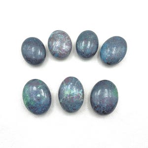 Puede incluir: Ocho piedras ovaladas con un patrón de mármol azul, verde y morado.