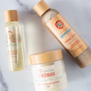 May include: Three personal care products with bamboo lids. A clear bottle with a yellow liquid labelled "geechee Lemongrass & Lemar", a brown bottle with a brown liquid labelled "geechee Herbal Sense Peppermint & Rosemary", and a white jar with a white cream labelled "geechee Freeman Green Tea, Vitamins, Minerals & Seaweed Organic Whipped Shea Moisturizer 250g".