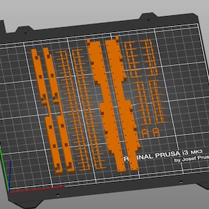 Peut inclure: Un plateau d'impression 3D avec une disposition d'impression orange. La disposition comprend diverses formes rectangulaires et lin&eacute;aires. Le texte "ORIGINAL PRUSA i3 MK3 by Josef Prusa" est visible.