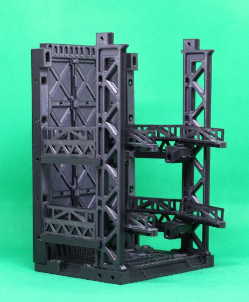 May include: A black, 3D-printed model of a futuristic industrial structure. The model features a complex network of support beams, platforms, and a large, closed door. The design suggests a sci-fi or architectural theme.