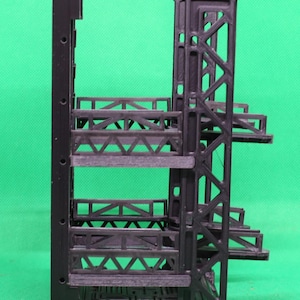 May include: A black, 3D-printed architectural model with multiple levels and a complex, geometric design. The model features a vertical support structure with horizontal platforms and intricate truss-like elements, showcasing a modern aesthetic.