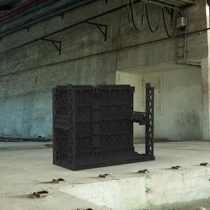 May include: A black, modular building structure with a complex, geometric design. The structure has a series of interconnected panels and a small platform extending from the side. The background is a concrete industrial space.