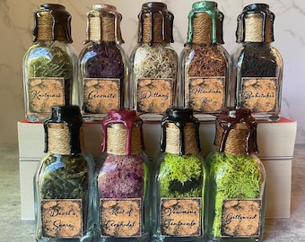 Puede incluir: Diez pequeños frascos de vidrio con tapones de corcho y etiquetas. Los frascos están llenos de hierbas secas y musgo. Las etiquetas tienen nombres como "Knotgrass", "Aconite", "Ditany", "Raíz de Mandrágora", "Bubotuber", "Lazo del Diablo", "Raíz de Asphodel", "Tentacula Venenosa", y "Gillyweed".