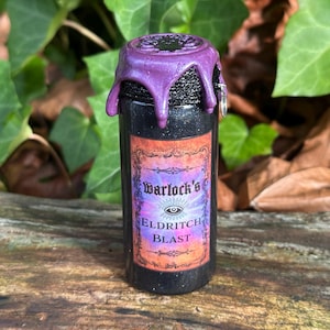 May include: A small, black bottle with a purple, dripped wax seal. The label reads "Warlock's Eldritch Blast" in ornate lettering. The bottle is set against a backdrop of green leaves and brown foliage, suggesting a natural setting.