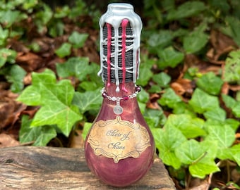 May include: A small glass bottle with a silver and red wax seal. The bottle is filled with a dark purple liquid and has a label that reads "Elixir of Chaos".