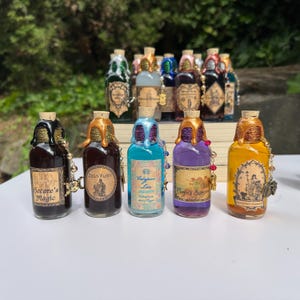 May include: A selection of decorative potion bottles with cork stoppers and ornate labels. The bottles contain liquids of various colours and are decorated with gold-coloured accents and charms. The labels include text such as "Becare's Magic" and "Zeus Fury".