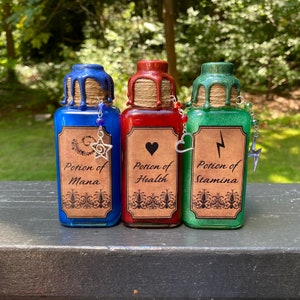 May include: Three small glass bottles with cork stoppers and labels. The bottles are filled with blue, red, and green liquids. The labels read "Potion of Mana", "Potion of Health", and "Potion of Stamina".