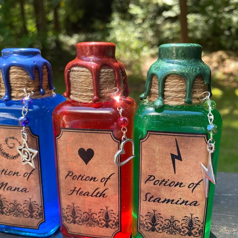 May include: Three glass bottles with cork stoppers and labels. The bottles are filled with blue, red, and green liquid. The labels read "Potion of Mana", "Potion of Health", and "Potion of Stamina".