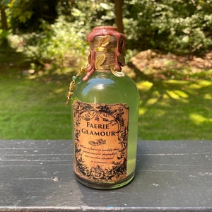 May include: A glass bottle with a brown wax seal and a label that reads "FAERIE GLAMOUR". The label has a decorative border and text that says "Allows a faerie to modify their appearance or shapeshift into another animal or creature."
