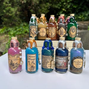 May include: A selection of decorative potion bottles with cork stoppers and colourful liquid contents. Each bottle has a unique label and is adorned with decorative elements like beads and charms. The bottles are arranged in front of a blurred green background.
