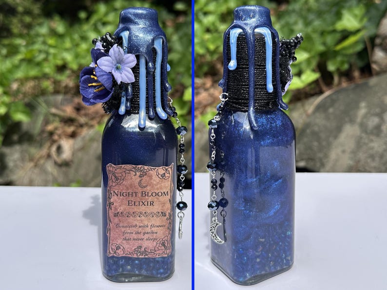 May include: A dark blue glass bottle labelled "Night Bloom Elixir." It features blue floral decorations, dripping blue wax, and a beaded chain with a crescent moon charm. The bottle's contents shimmer with blue glitter, creating a magical aesthetic.