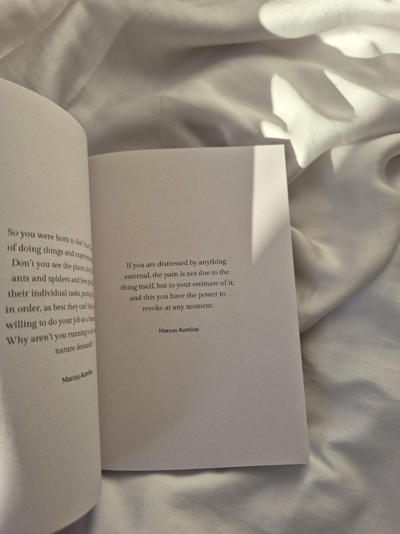 May include: A white book with a quote from Marcus Aurelius about pain and distress. The quote reads: "If you are distressed by anything external, the pain is not due to the thing itself, but to your estimate of it; and this you have the power to revoke at any moment."