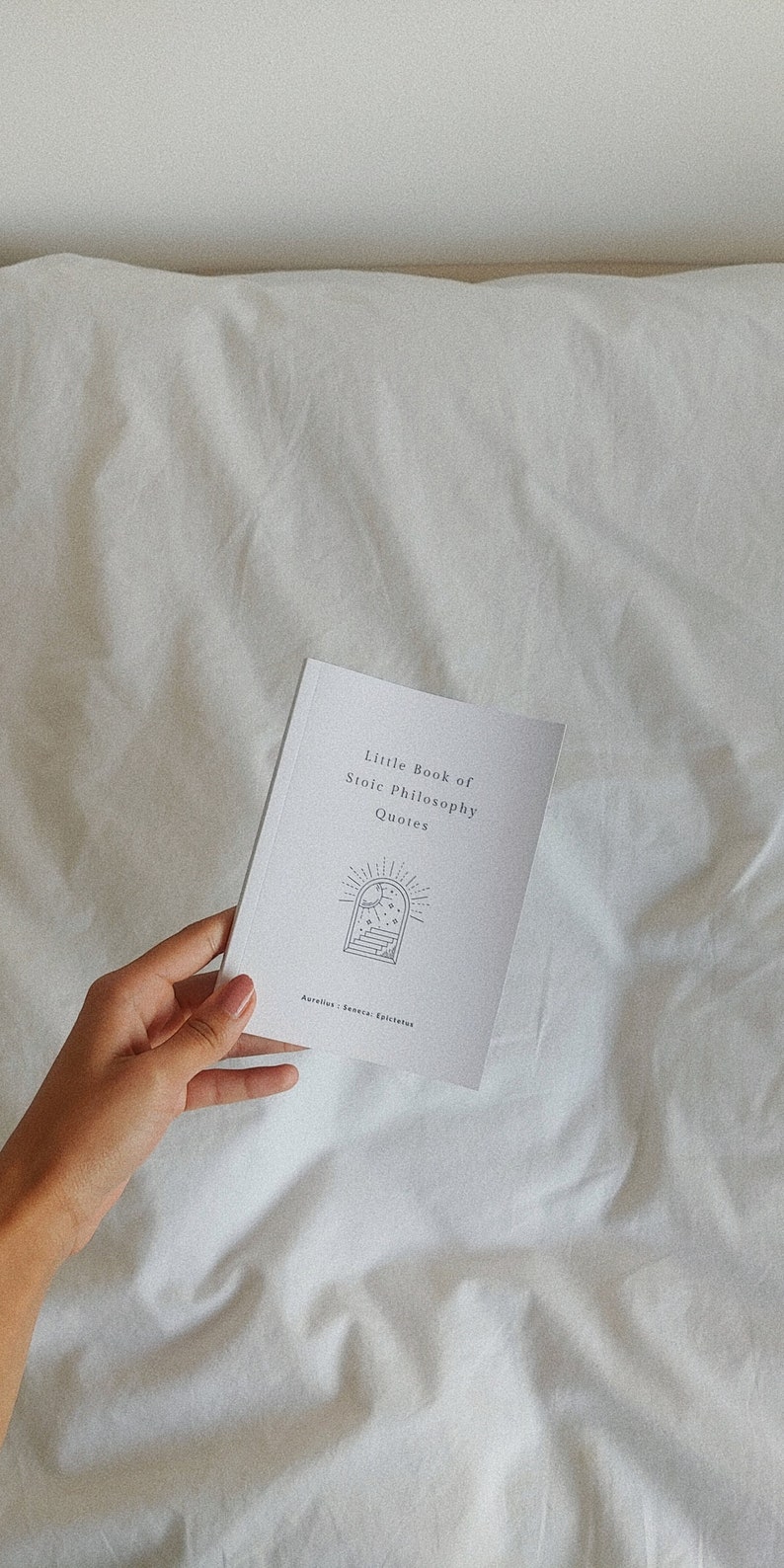 May include: A white booklet with the title "Little Book of Stoic Philosophy Quotes" and a black and white illustration of a window with stars and a staircase. The text "Aurelius, Seneca, Epictetus" is printed at the bottom of the booklet.
