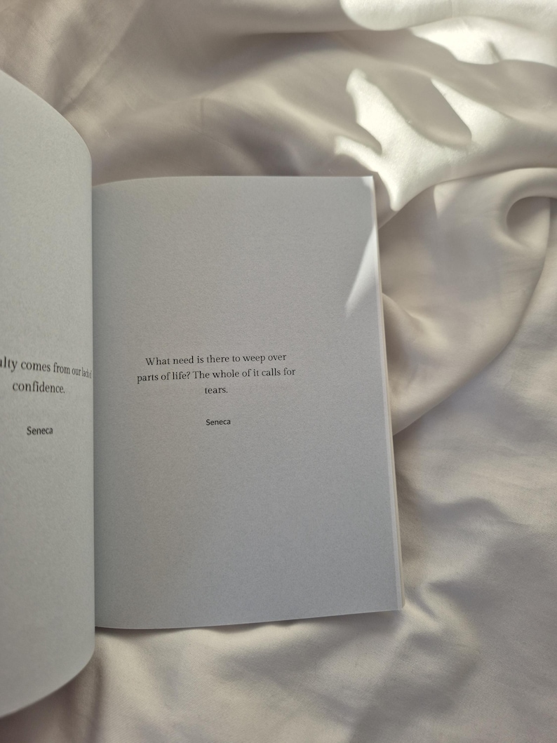 May include: An open book with a white background. The text on the page reads: "What need is there to weep over parts of life? The whole of it calls for tears. Seneca"