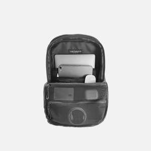 May include: A black backpack with a laptop, phone, and mouse inside. The backpack has a mesh pocket on the front and a zippered pocket on the side.