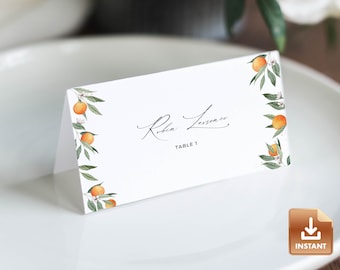 May include: White place card with a floral design featuring orange blossoms and fruit. The text "Robin Lawrence" and "Table 1" is printed on the card.