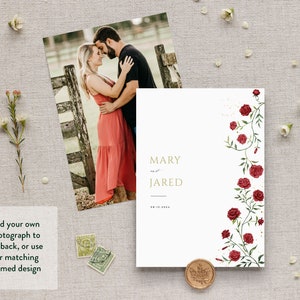 May include: A white wedding invitation with a gold border and the names "MARY and JARED" printed in gold. The invitation features a floral design with red roses and green leaves on the right side.