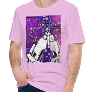 May include: A light pink t-shirt featuring a detailed graphic illustration. The artwork includes a central figure with mechanical elements, set against a purple and blue geometric background. The artist's signature, "R.G. Foster," is visible.