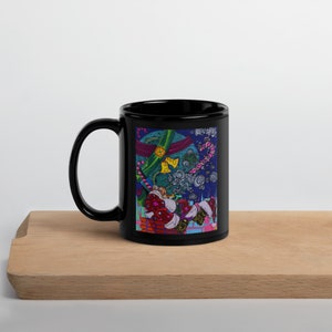 Può includere: Tazza da caffè in ceramica nera con un'illustrazione colorata di una persona in un camino su uno sfondo di cielo stellato.