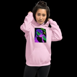 May include: A pink hoodie with a graphic print of a black cat and a green and purple creature on the front.