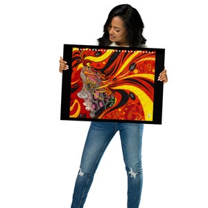 May include: A person is holding a framed abstract art print with a colorful design featuring a woman's face with red, yellow, black, and white colors.