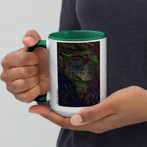 May include: White ceramic mug with a green rim and handle. The mug features a colorful abstract design with a black and white signature that reads "B.G. Foster".