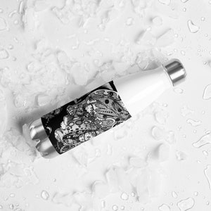 May include: A black and white patterned stainless steel water bottle with a screw-on lid. The bottle is lying on a white surface with ice.