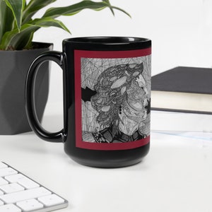 May include: Black ceramic mug with a red border and a black and white line drawing of a person's face. The drawing is detailed and intricate.