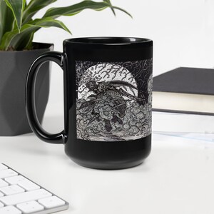 May include: Black ceramic mug with a white and black illustration of a creature with wings flying through the clouds and a full moon in the background.