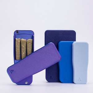 May include: A set of four small, rectangular cases in shades of blue and purple. The largest case is open, revealing three brown, cylindrical objects inside. The cases have a textured surface and a small triangle logo on the front.
