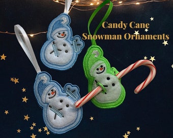 May include: Embroidered snowman ornaments with blue and green hats, holding ski poles, and candy canes. The ornaments have white ribbon hangers. Text on the image reads "Candy Cane Snowman Ornaments".