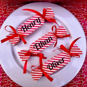 Peut inclure: Trois crackers de Noël en forme de canne de bonbon rouge et blanche avec les noms Henry, Ethan et Oliver imprimés dessus.