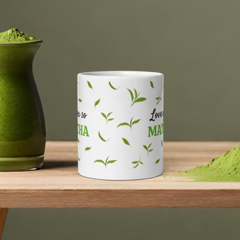 Peut inclure: Une tasse en c&eacute;ramique blanche avec un motif de feuilles vertes et le texte "Love you so matcha" imprim&eacute; dessus.