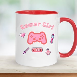 Op de afbeelding: Witte keramische mok met een rode rand en handvat. De mok heeft een roze gamer girl-ontwerp met een roze videogamecontroller, een roze diamant, een roze zwaard, een roze drankfles, een roze parfumfles en een roze "START"-knop.