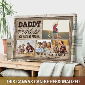 Puede incluir: Un lienzo personalizado enmarcado con fotos familiares y texto. El texto dice "DADDY to the World, You are one person, but to us you are the world." La parte inferior del lienzo dice "THIS CANVAS CAN BE PERSONALIZED." El marco es de madera.