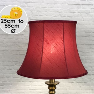 May include: A bell-shaped lampshade in a deep red fabric with a subtle textured finish and braided trim along the top and bottom edges. A circular graphic shows a yellow measuring tape with text indicating a diameter range of 25cm to 55cm.