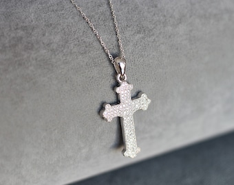 May include: A silver necklace with a diamond-encrusted cross pendant. The cross is a traditional design with a slightly rounded shape.