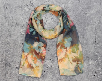 May include: A floral patterned scarf in shades of blue, yellow, pink, and brown. The scarf is made of a lightweight fabric and has a soft, flowing drape.