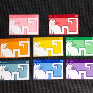 Op de afbeelding: Zeven kleurrijke stickers met een witte kat in een computerfoutvenster. Elke sticker heeft een andere achtergrondkleur: roze, rood, oranje, geel, groen, blauw en paars. Het woord "Error" staat bovenaan afgedrukt.